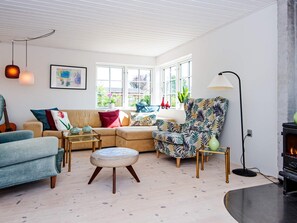 Una sala moderna con un sofá, un sillón, un reposapiés y una chimenea.