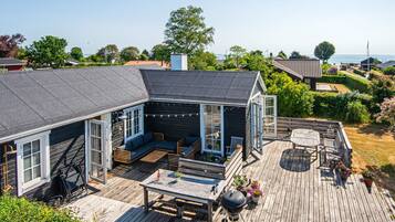 A house with a deck, outdoor seating, and a view of the sea.