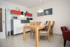 A compact kitchen with modern appliances, a dining table with wicker chairs, and a red sofa. - Apartment mit Balkon Nahe am Erlebnisberg Kappe (Winterberg)