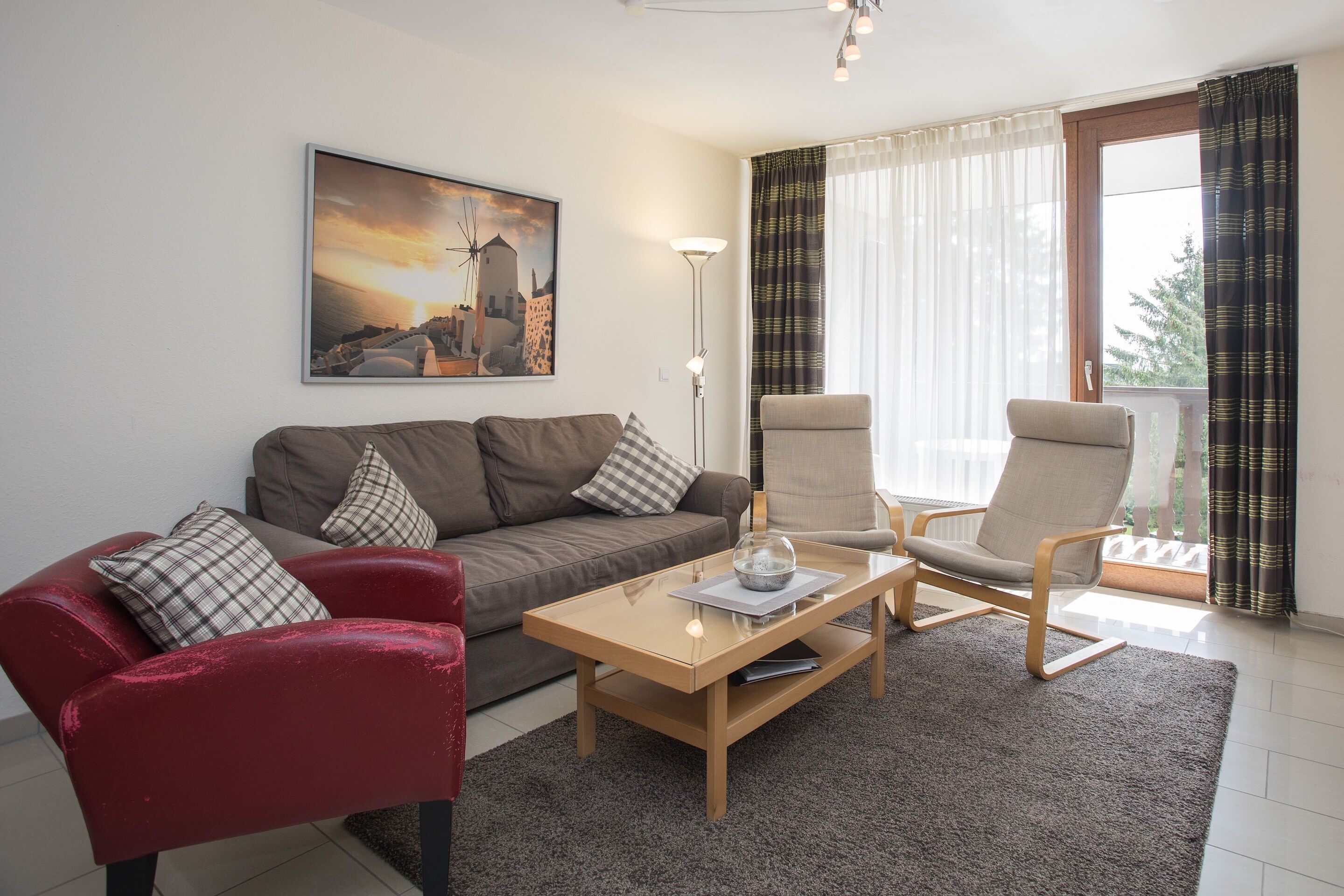 Ein Wohnzimmer mit Sofa, Sesseln, Couchtisch und einem Gemälde an der Wand.