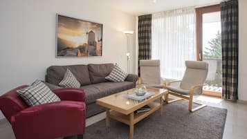 Un salon avec un canapé, un fauteuil, une table basse et un tableau accroché au mur.