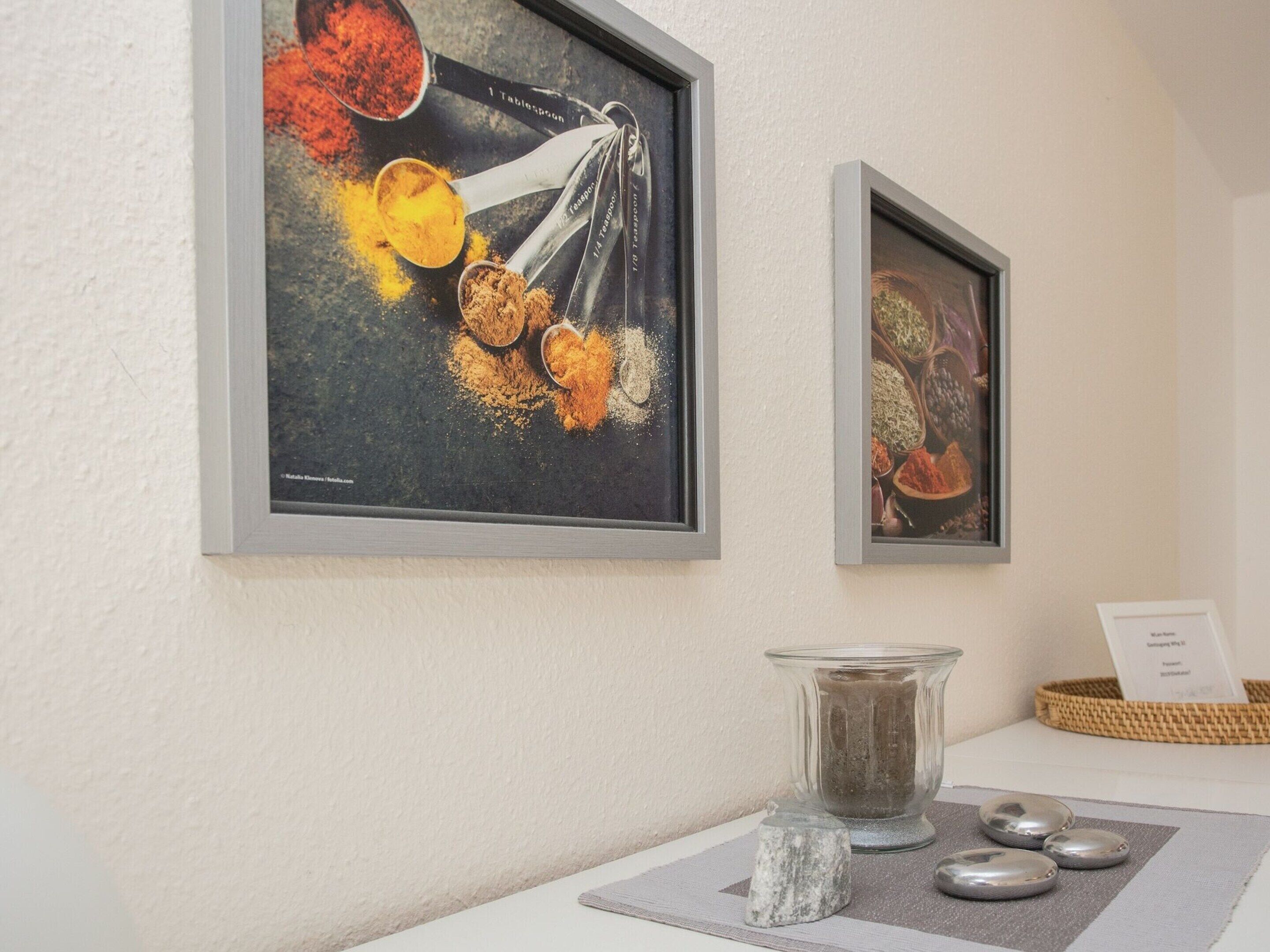 Two framed artworks depicting spices and grains on a wall.