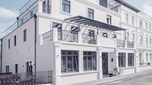 A multi-story building with white exterior walls, large windows, and balconies with metal railings. - 3 in het Huis Meerloft (Norderney)