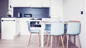 A modern kitchen with white cabinets, a black countertop, and a dining area with a table and four chairs. - 3 in het Huis Meerloft (Norderney)