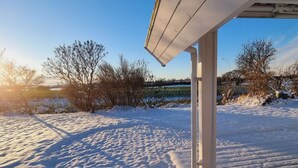 A snowy outdoor area with a building's roof and columns. - Holiday Home sea Waves (Brodersby)