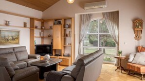 A living room with a sofa set, a television, wooden shelves, and a large window with curtains. - Villa Rosy Comfortable Holiday Residence (Rovinj)