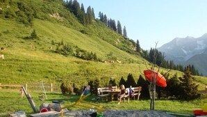 Ein Picknickbereich mit Tisch, Stühlen und einem roten Sonnenschirm.