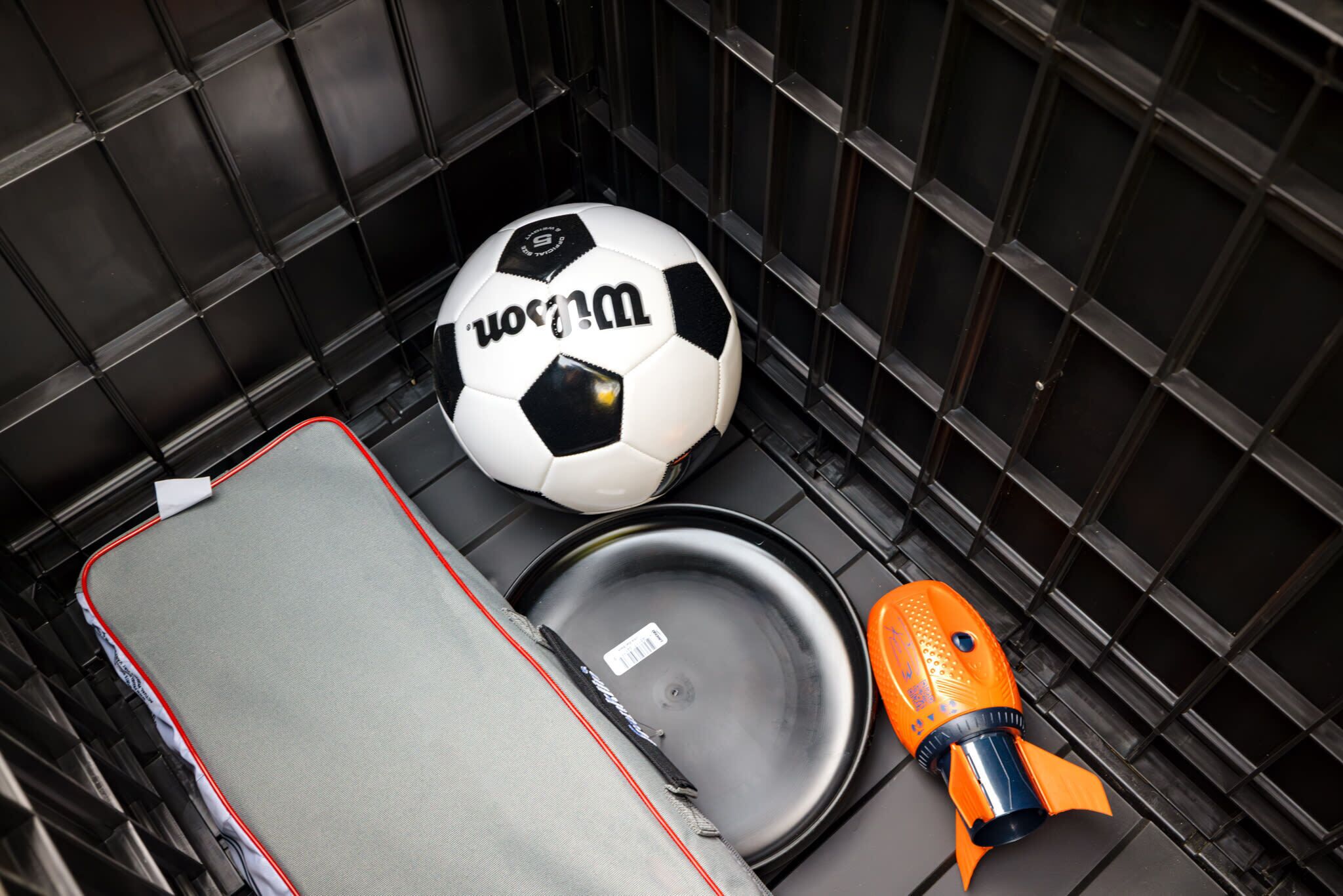 A suitcase, a soccer ball, and a toy rocket inside a compartment.