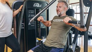 Et fitnessrum med træningsudstyr, herunder en brystpresmaskine og en siddende ro-maskine.