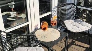 A deck with two black chairs and a table, two glasses of red drink, and a decorative fish on the window. - Holiday Apartment Lust on Sylt (Sylt)