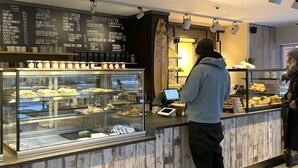 A bakery counter with a glass display case filled with pastries and a menu board above it listing various items. - Holiday Apartment Lust on Sylt (Sylt)