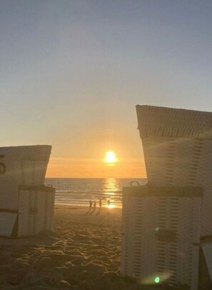 A beach scene with sunlit horizon, two beach chairs, and a few people in the distance. - Holiday Apartment Lust on Sylt (Sylt)