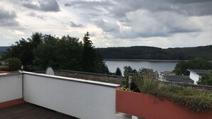 A rooftop terrace with a view of a lake and forested hills. - Holiday Apartment Siuerlanner (Sundern)