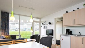 Een moderne keuken met een eethoek, een televisie en een kleine koelkast.