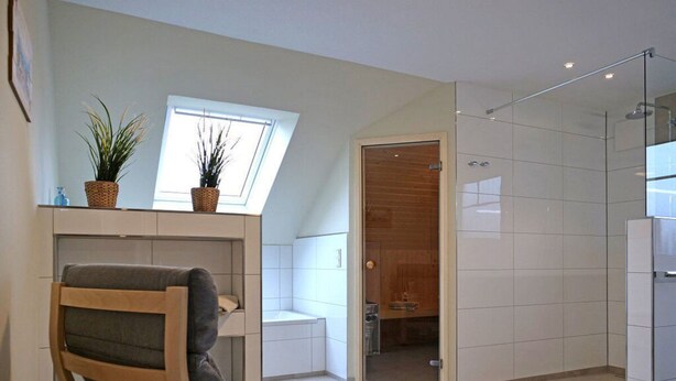 A modern kitchen with white cabinets, a built-in oven, and a window above the sink. - Holiday Home sea Breeze (Butjadingen)