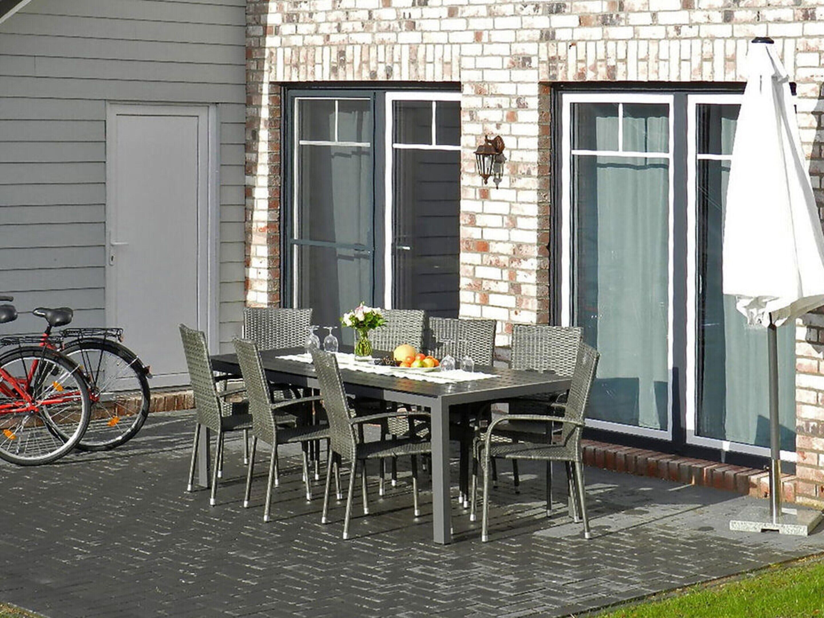 An outdoor patio with a table and chairs, a bicycle, and a brick wall.