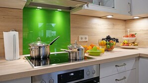 A modern kitchen with a green backsplash, stainless steel appliances, and a fruit bowl on the counter. - Holiday Home sea Breeze (Butjadingen)