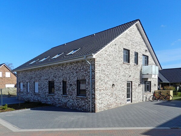 A modern two-story building with a stone facade, multiple windows, and a sloped roof.