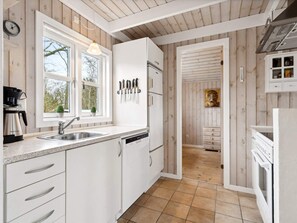 A kitchen with white cabinets, a sink, a coffee maker, and a knife rack. - 4 Person Holiday Home in Hemmet (Hemmet)
