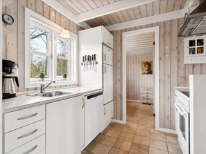 A kitchen with white cabinets, a sink, a coffee maker, and a knife rack. - 4 Person Holiday Home in Hemmet (Hemmet)