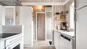 A modern kitchen with a stove, oven, and dishwasher, wooden paneling, and a door leading to another room. - 4 Person Holiday Home in Hemmet (Hemmet)