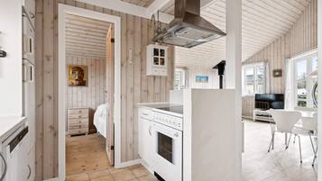 A modern kitchen with wooden paneling, a built-in oven, and a dining area with a TV.
