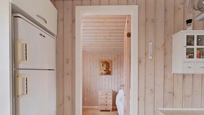 A narrow hallway with wooden walls, a white cabinet with glass doors, and a white refrigerator on the left. - 4 Person Holiday Home in Hemmet (Hemmet)