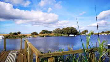 A wooden dock extending into a calm body of water with boats docked nearby and a clear sky above.
