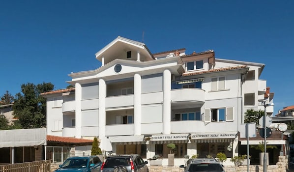 A multi-story building with a restaurant named "RESTAURANT VILLA MARGERITA" on the ground floor. There are several balconies and a clear blue sky in the background. - Donatella -apt 2- met Zeezicht (Medulin)