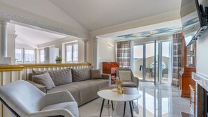 A spacious living room with a sofa, armchairs, and a coffee table. There is a fireplace, a television, and a view of the outside. - Donatella -apt 2- met Zeezicht (Medulin)