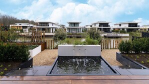 A modern residential area with contemporary houses, a central water feature, and a clear sky. - Villa in Zeewolde Near Town Center (Zeewolde)