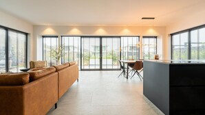 A modern kitchen with a dining area, large windows, and a sofa. - Villa in Zeewolde Near Town Center (Zeewolde)