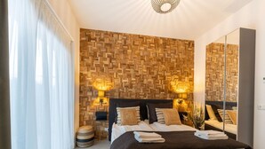 A modern bedroom with a wooden wall panel, a large bed with multiple pillows, bedside tables, and a mirror. - Villa in Zeewolde Near Town Center (Zeewolde)