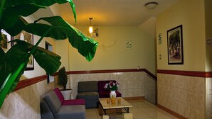 A lobby with a sofa, a coffee table with drinks, a potted plant, and a wall-mounted sign. - TERRAMISTICA CENTRO BY CASA CONSUELO   (Arequipa)