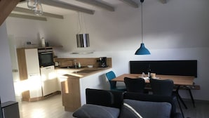 A modern apartment with a kitchenette, dining area, and a cozy seating area with a sofa and chairs. - Holiday Home Tim Paul (Butjadingen)