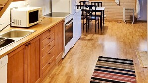 Un angolo cottura compatto con mobili in legno, un forno a microonde, un forno e un'area pranzo con tavolo e sedie.