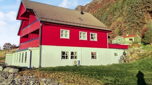 Una casa rossa e bianca con un tetto spiovente, sullo sfondo di montagne.