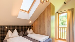 A bedroom with a skylight, wooden panel walls, a bed with pillows, and a view of greenery outside. - Chalet in Wolting With Natural Swimming Pond (Tamsweg)