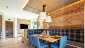 A modern dining area with a wooden table, blue upholstered chairs, and a bench. - Chalet in Wolting With Natural Swimming Pond (Tamsweg)