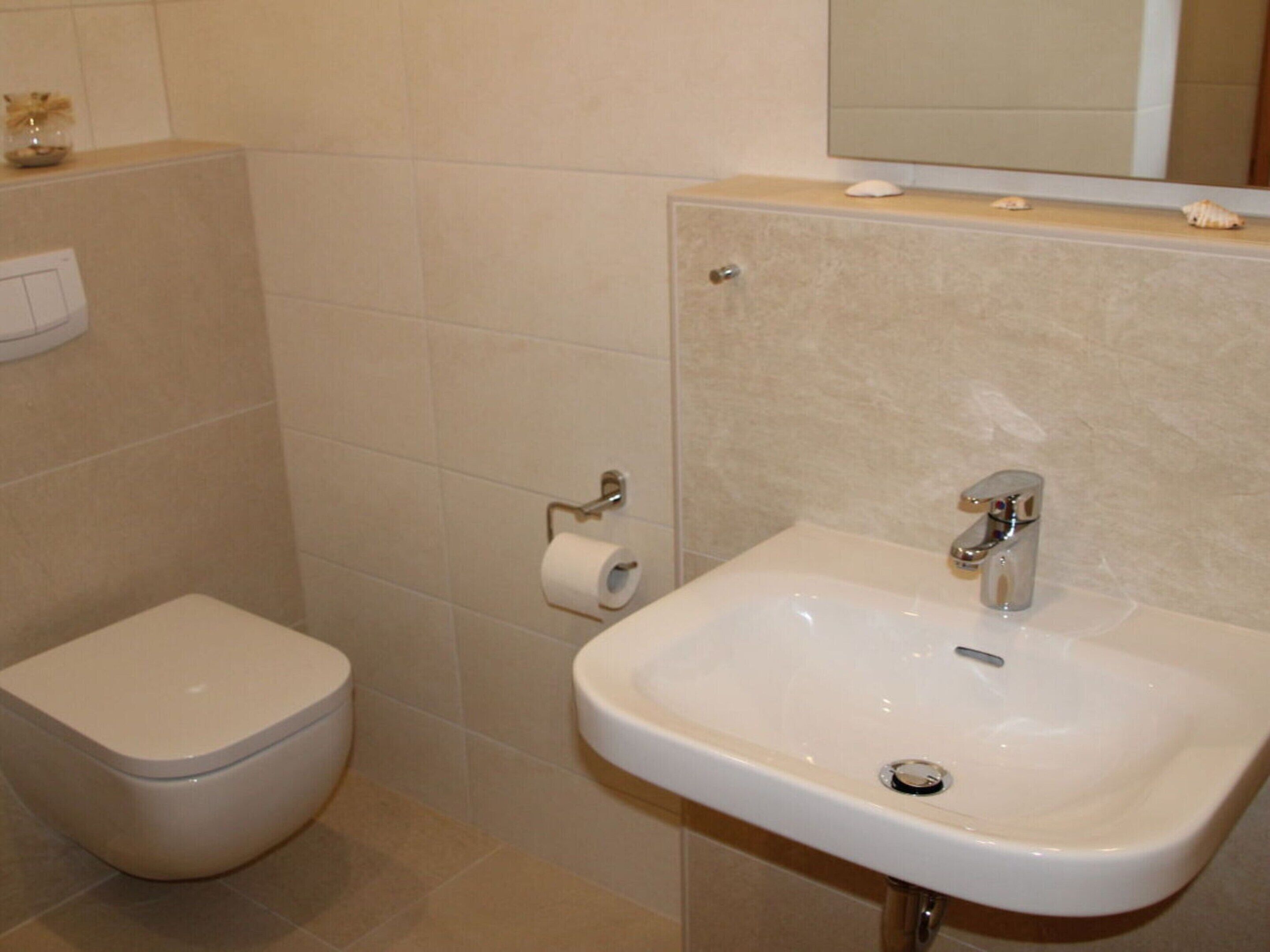 Un baño con inodoro, lavamanos y espejo.