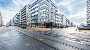 A modern urban street with multi-story buildings, a tram line, and parked cars. - Studio With Sleeping Area for Family (Middelkerke)