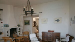 Una sala de estar acogedora con muebles de mimbre, chimenea y una escalera que sube.