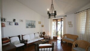 Una sala de estar acogedora con un sofá, sillas, una mesa de comedor y una araña.