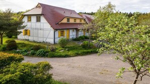 A two-story house with a red-tiled roof, surrounded by greenery and a gravel driveway. - Comfortplus Apartment With 1 Bedroom (Dranske)