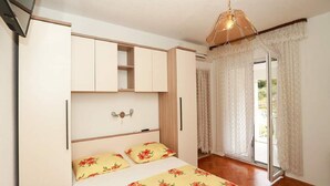 A bedroom with a bed, a wardrobe, and a window with curtains. - Apartments Pezo - Superior Two Bedroom Apartment With Balcony (Baska Voda)