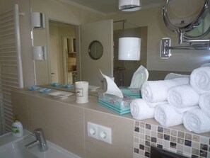 A bathroom with a sink, mirror, towel rack, and a shower area. - Deck 3 Modern Retreat (Timmendorfer Strand)