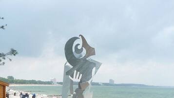 A beachside sculpture with a clear view of the sea and beach chairs in the background.