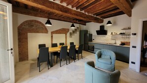 A dining area with a wooden table and chairs, a kitchen with modern appliances, and exposed wooden beams on the ceiling. - Apartment sleeps 6 located in in the heart  Asciano, with terrace. (Asciano)
