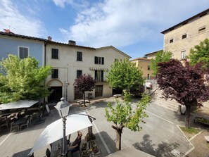 A courtyard with outdoor seating, a street, and buildings with traditional architecture.