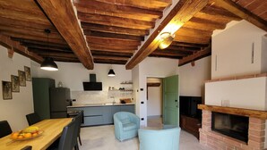 A modern kitchen with a dining area, a fireplace, and a light blue armchair. - Apartment sleeps 6 located in in the heart  Asciano, with terrace. (Asciano)